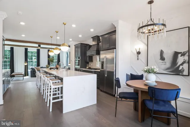 a large kitchen with stainless steel appliances a large center island attached withe living room