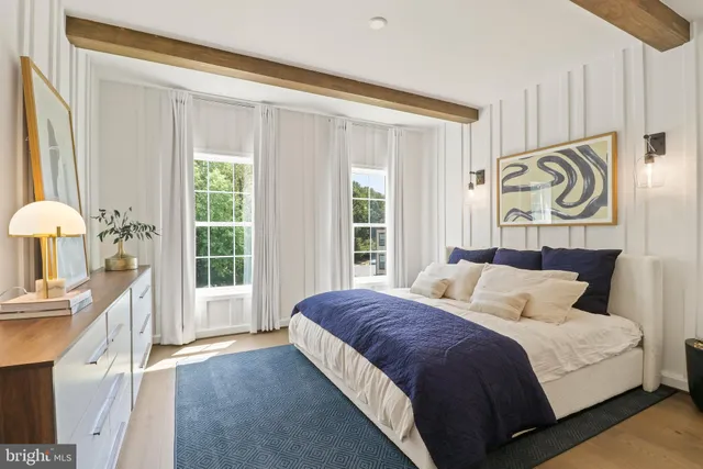 a large white bed sitting in a bedroom next to a window