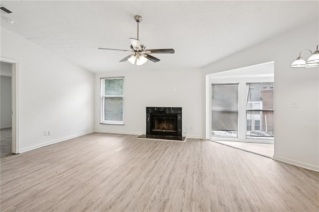 4263 Parkview Court Stone Mountain, GA 30083 - Photo 9 of 31 an empty room with wooden floor fireplace and windows