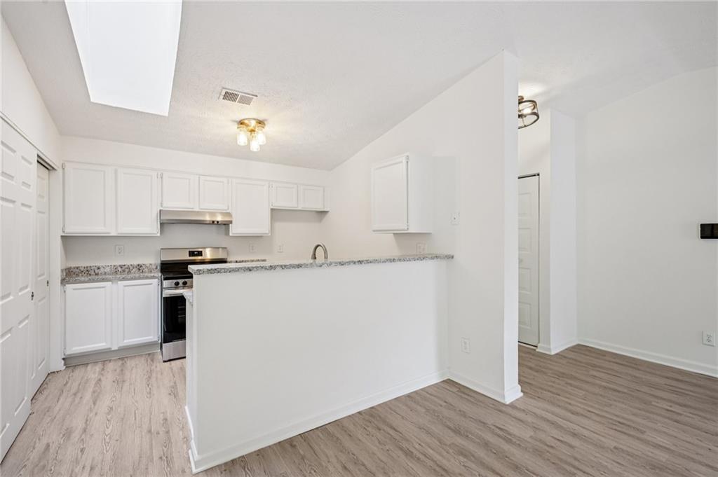 4263 Parkview Court Stone Mountain, GA 30083 - Photo 10 of 31 a kitchen with stainless steel appliances granite countertop a refrigerator a stove and white cabinets with wooden floor