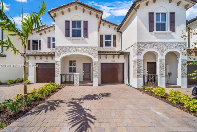 a front view of a house with yard and parking