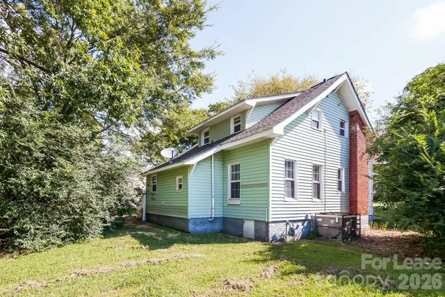 a view of a house with a yard plants and large tree