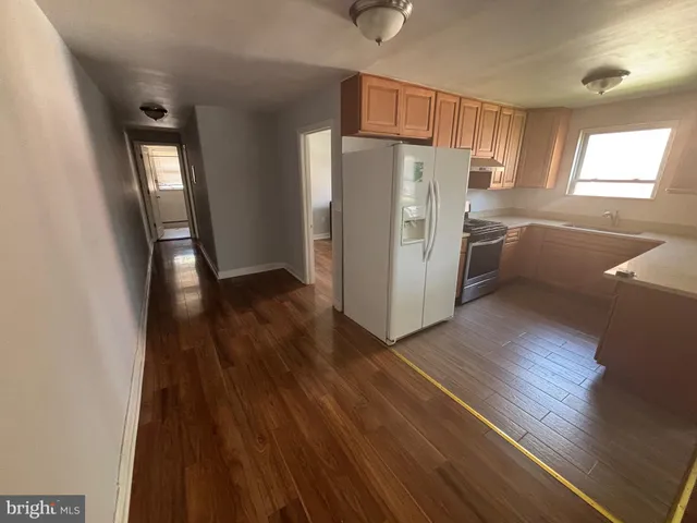 a kitchen with granite countertop a refrigerator a sink and wooden floors
