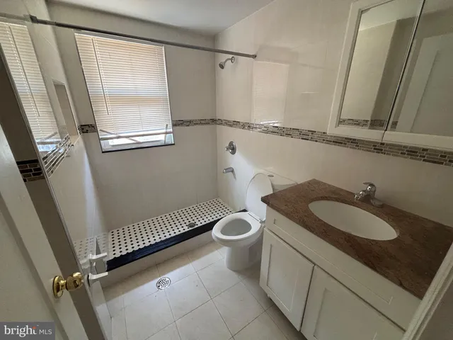 a bathroom with a granite countertop sink a toilet a mirror and a shower