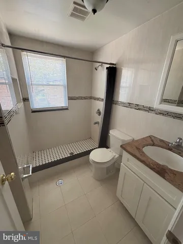 a bathroom with a granite countertop sink a mirror and a toilet