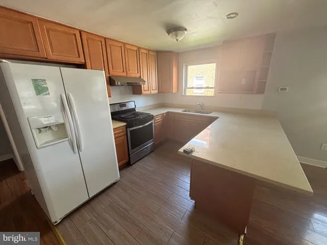 a kitchen with wooden floors and white stainless steel appliances
