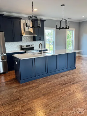 a kitchen with stainless steel appliances granite countertop a stove a sink and a wooden floors