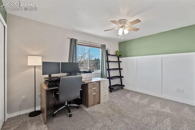 a view of an empty room with chandelier fan and fire place