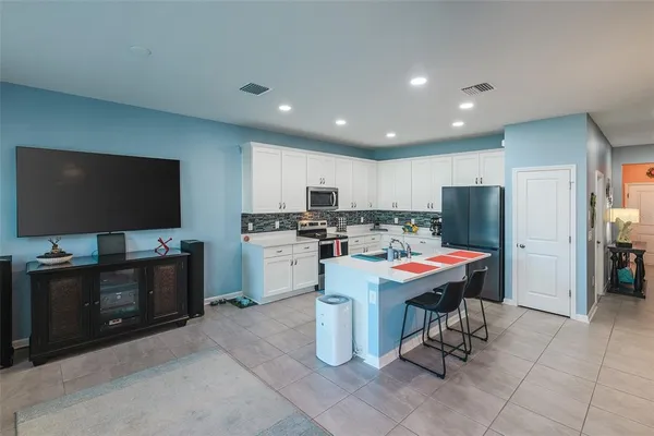 a living room with stainless steel appliances kitchen island granite countertop furniture and a flat screen tv