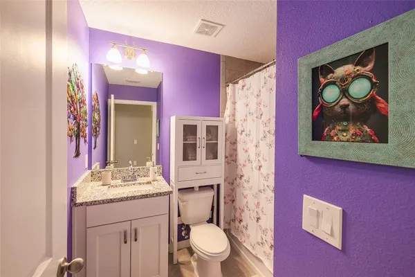 a bathroom with a granite countertop sink a toilet and shower