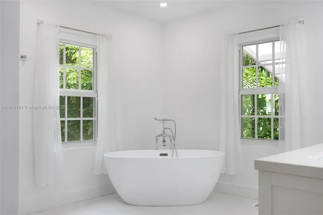 a white bath tub sitting in a bathroom next to a window