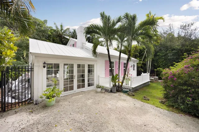 a view of a house with a small yard and large trees