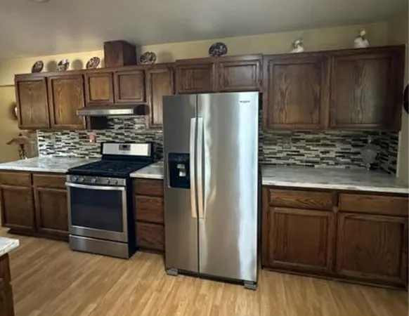 a kitchen with stainless steel appliances granite countertop a refrigerator and a stove