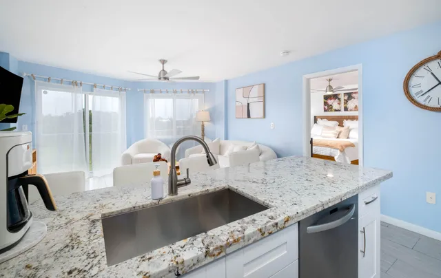 a kitchen with granite countertop a sink a counter top space cabinets and stainless steel appliances