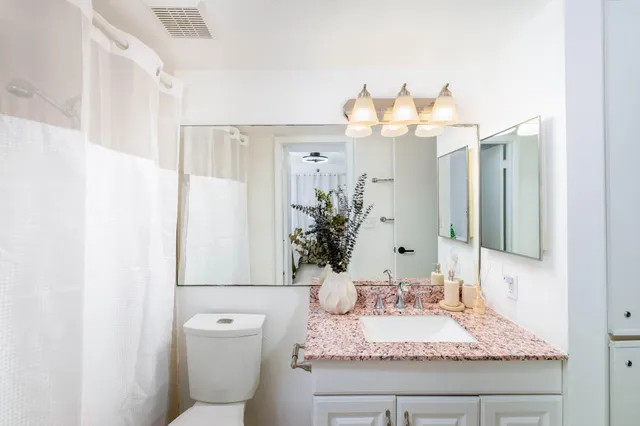 a bathroom with a granite countertop sink a toilet and a mirror