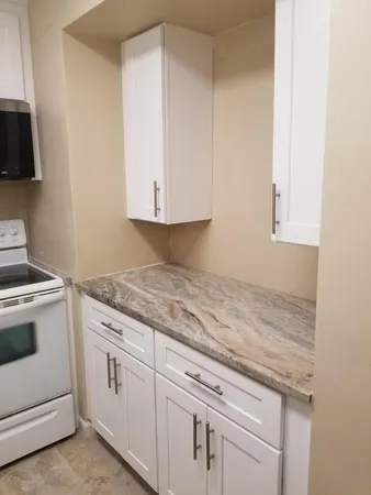 a kitchen with granite countertop white cabinets and white appliances