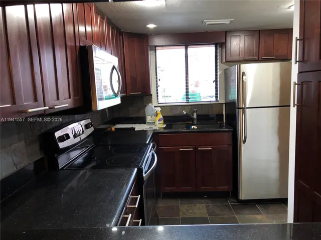 a kitchen with a refrigerator a stove a sink and a window