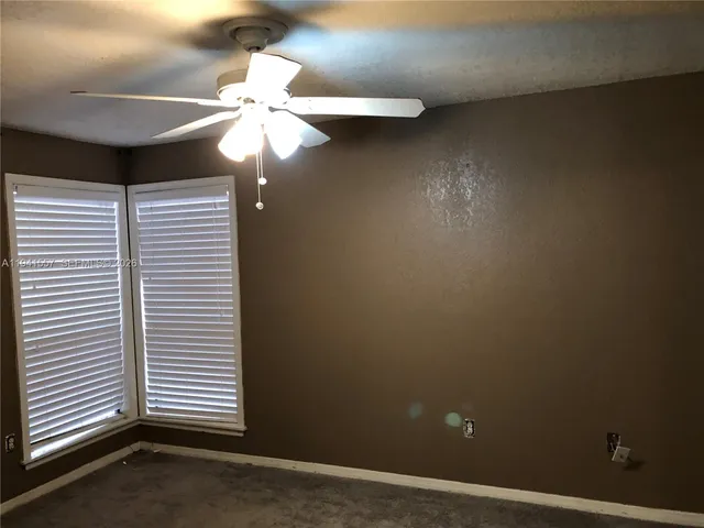 an empty room with a ceiling fan and a window