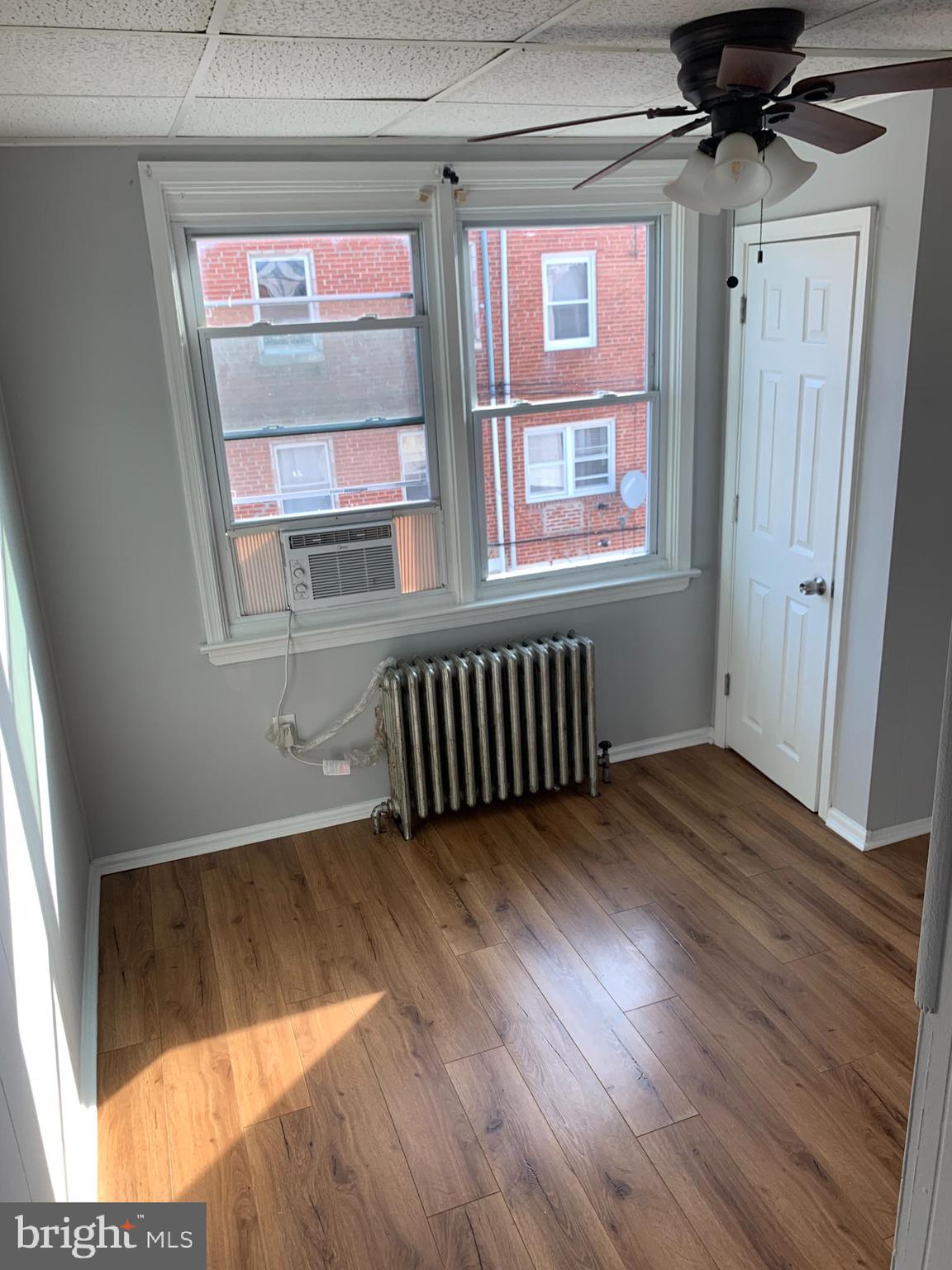 4135 Gilham Street Philadelphia, PA 19135 - Photo 5 of 12 a view of an empty room with a window and wooden floor