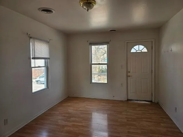 a view of an empty room with wooden floor and a window
