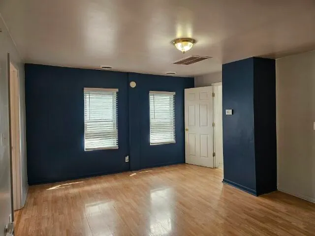 a view of empty room with window and wooden floor