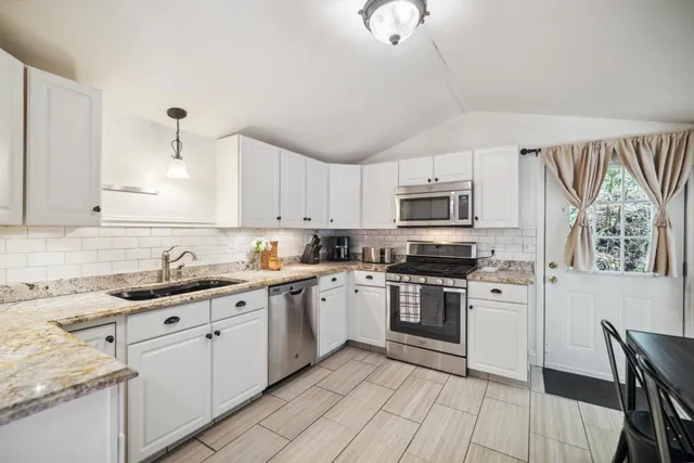 a kitchen with stainless steel appliances a stove a sink cabinets and a dining table