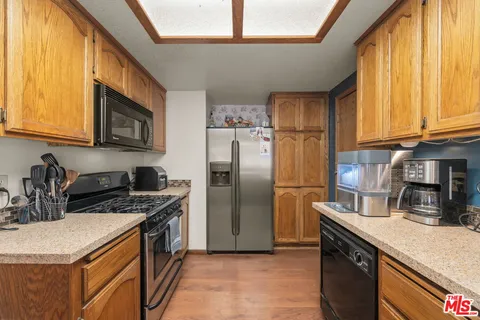 a kitchen with stainless steel appliances granite countertop a refrigerator a sink a stove and a microwave