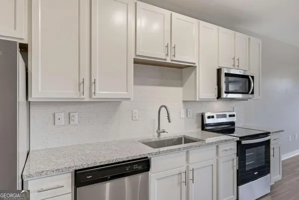 a kitchen with white cabinets and stainless steel appliances
