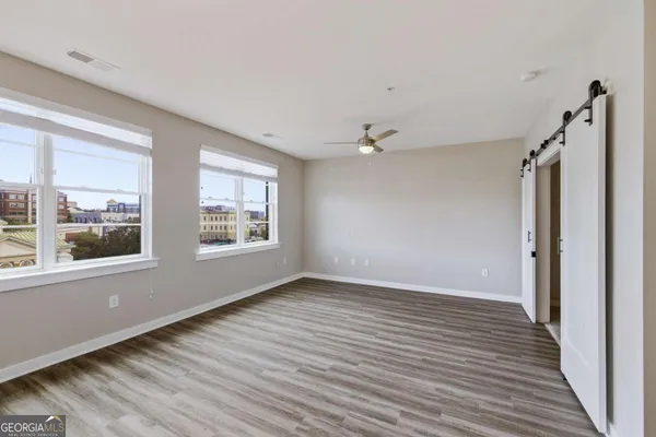 a view of an empty room with wooden floor and a window