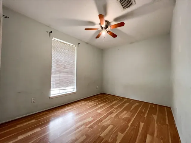 an empty room with wooden floor fan and windows