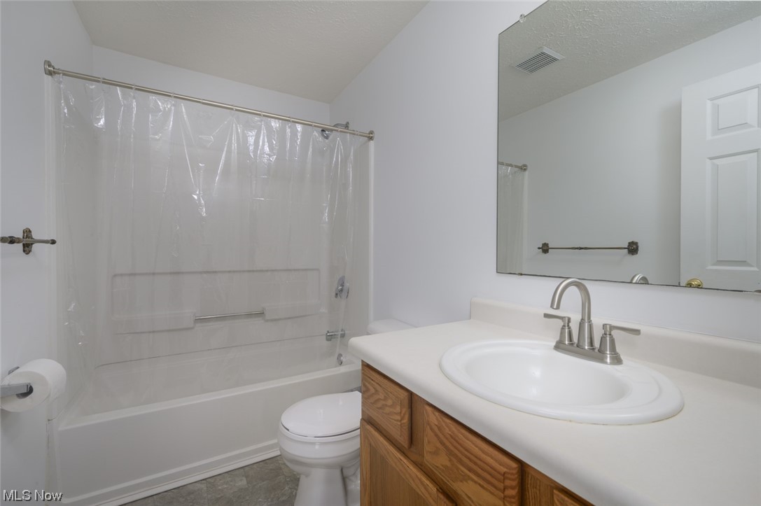 8045 State Rte 5 Ravenna, OH 44266 - Photo 23 of 32 Full bathroom featuring vanity, a textured ceiling, mirror, shower / bathtub combination with curtain, and light tile floors