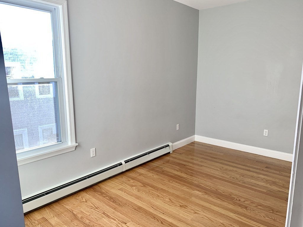 107 Chelsea Street, Unit 3 Boston, MA 02128 - Photo 13 of 15 a view of an empty room with wooden floor and a window