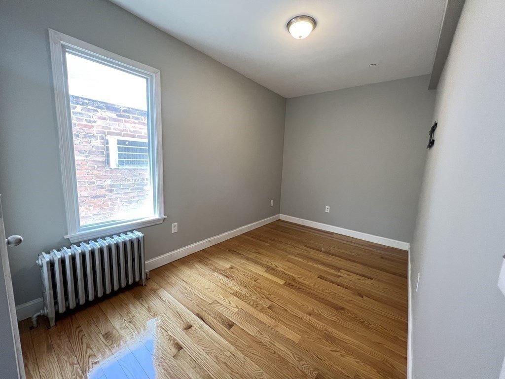 107 Chelsea Street, Unit 3 Boston, MA 02128 - Photo 14 of 15 a view of an empty room with wooden floor and a window