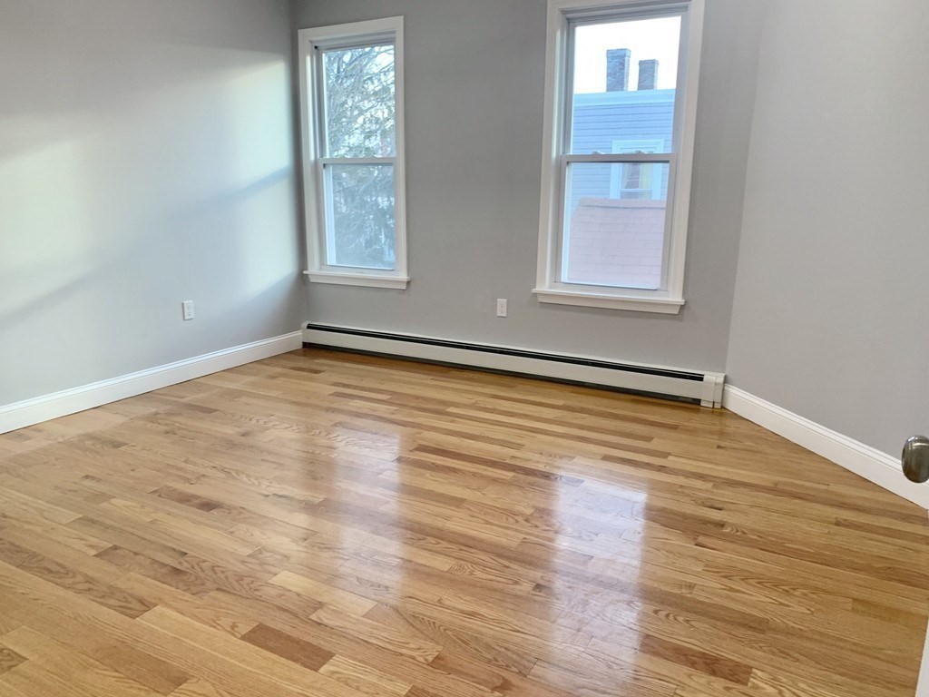 107 Chelsea Street, Unit 3 Boston, MA 02128 - Photo 3 of 15 a view of an empty room with wooden floor and a window