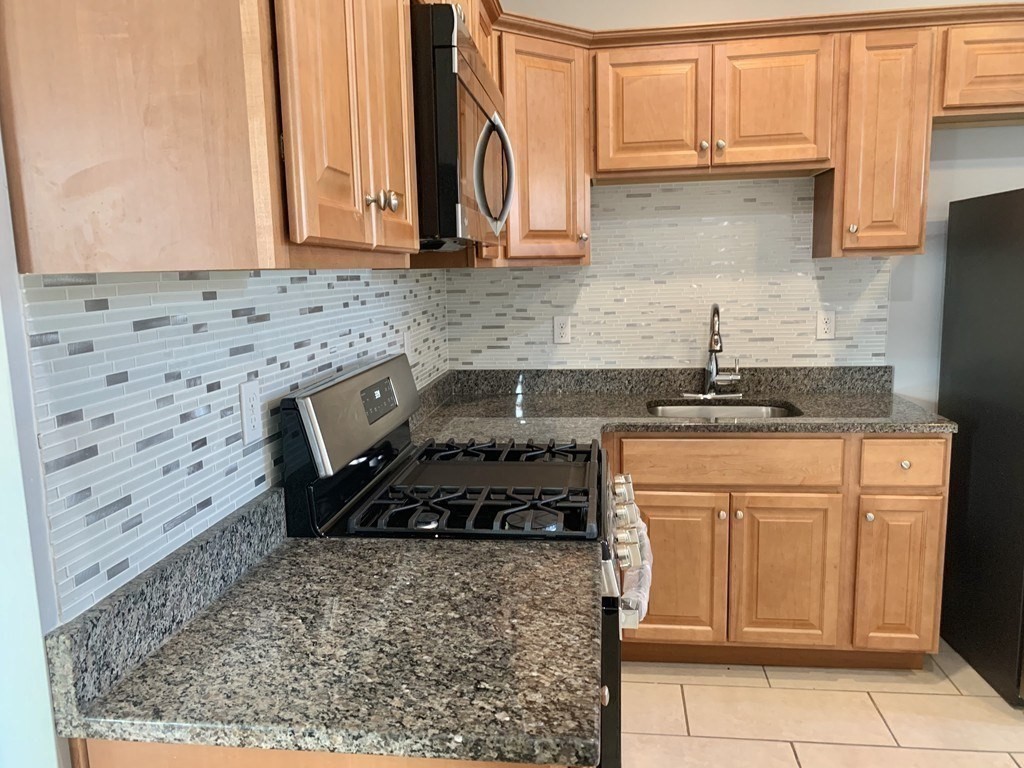 107 Chelsea Street, Unit 3 Boston, MA 02128 - Photo 9 of 15 a kitchen with granite countertop a stove a sink and a microwave