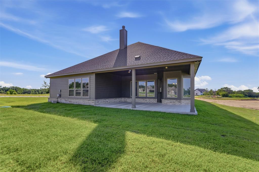 605 Tay Tay Way Springtown, TX 76082 - Photo 29 of 31 Rear exterior featuring a covered patio, dark gray siding, a stone accent foundation, a gabled roofline, and a prominent chimney