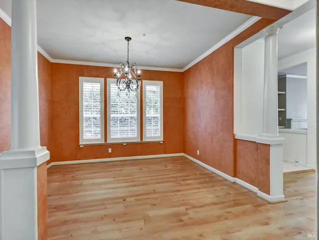 a view of an empty room with window and hardwood floor