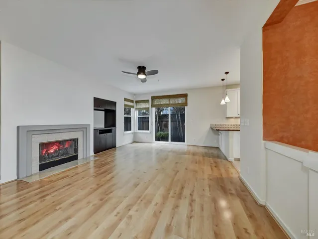 a view of an empty room with a kitchen and a fireplace