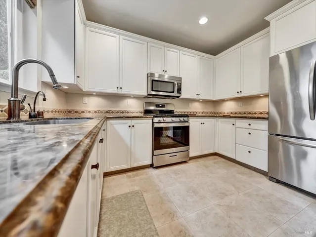 a kitchen with stainless steel appliances granite countertop a stove top oven a sink refrigerator and cabinets