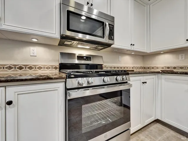 a kitchen with stainless steel appliances granite countertop a stove microwave and cabinets