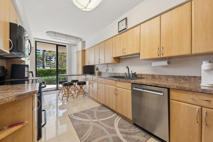 1401 South Ocean Boulevard, Unit 110 Boca Raton, FL 33432 - Photo 7 of 46 a kitchen with stainless steel appliances granite countertop a stove top oven a sink dishwasher a dining table and chairs with wooden floor