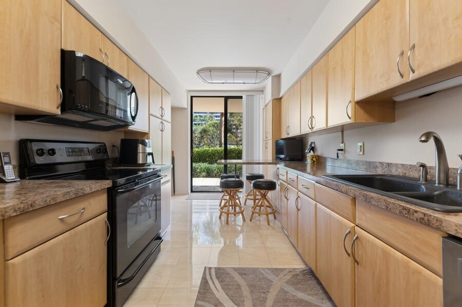 1401 South Ocean Boulevard, Unit 110 Boca Raton, FL 33432 - Photo 8 of 46 a kitchen with stainless steel appliances granite countertop a stove top oven a sink dishwasher a dining table and chairs with wooden floor