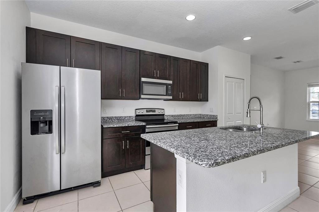 3650 Southwest 128th Place Ocala, FL 34473 - Photo 14 of 40 a kitchen with a sink a refrigerator a microwave and cabinets
