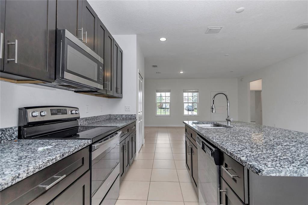 3650 Southwest 128th Place Ocala, FL 34473 - Photo 16 of 40 a kitchen with stainless steel appliances granite countertop a stove and cabinets