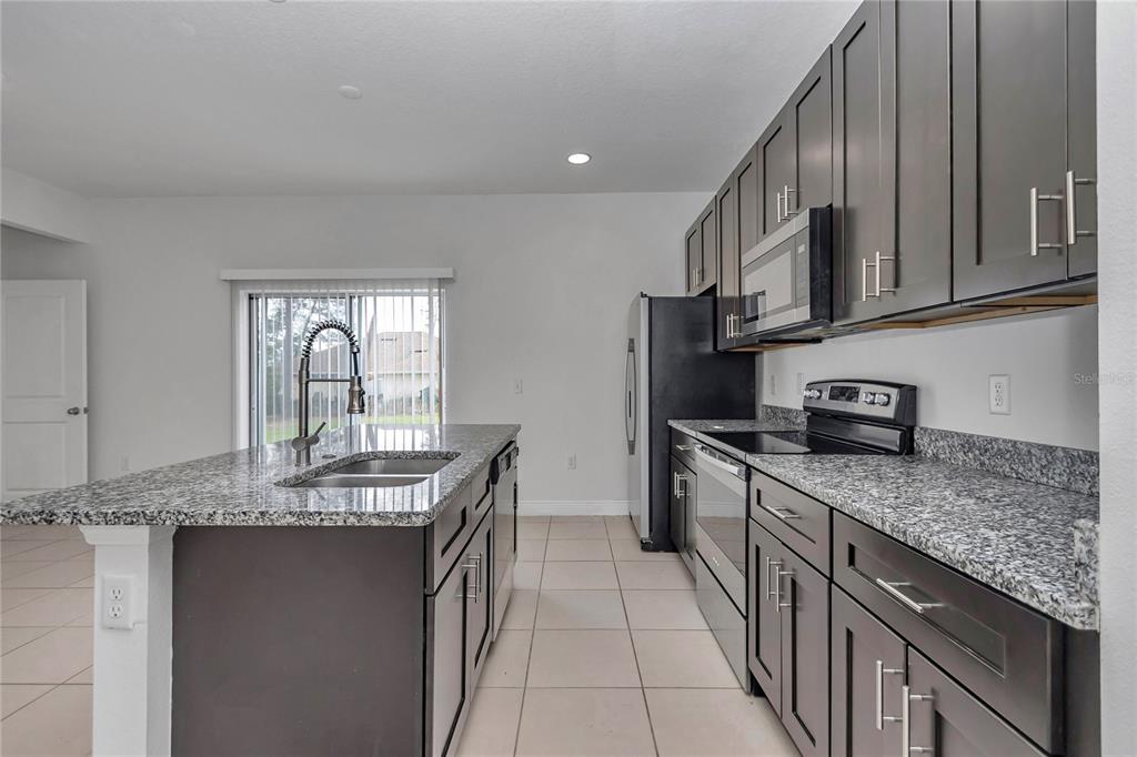 3650 Southwest 128th Place Ocala, FL 34473 - Photo 17 of 40 a kitchen with stainless steel appliances granite countertop a sink stove and cabinets