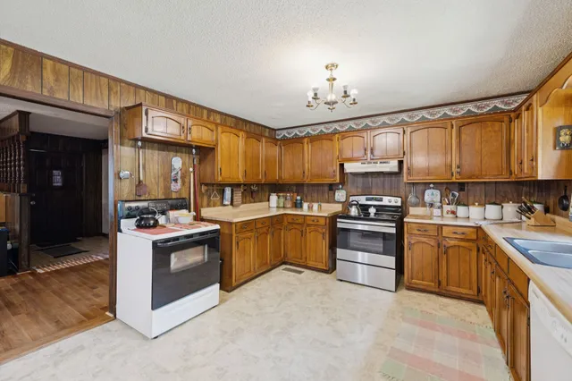 a kitchen with stainless steel appliances granite countertop a stove top oven a sink dishwasher a refrigerator and cabinets with wooden floor