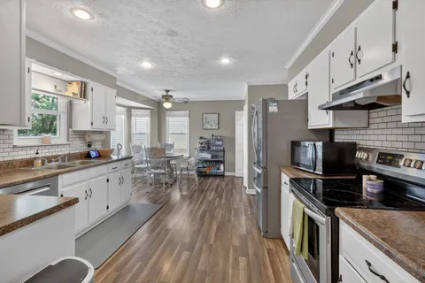 a kitchen with a sink appliances wooden floor and a window