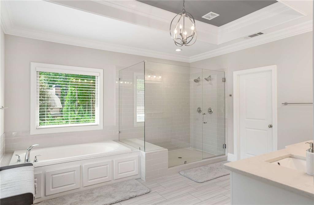 5055 Pointer Ridge Flowery Branch, GA 30542 - Photo 31 of 79 a bathroom with a tub a sink and a large mirror