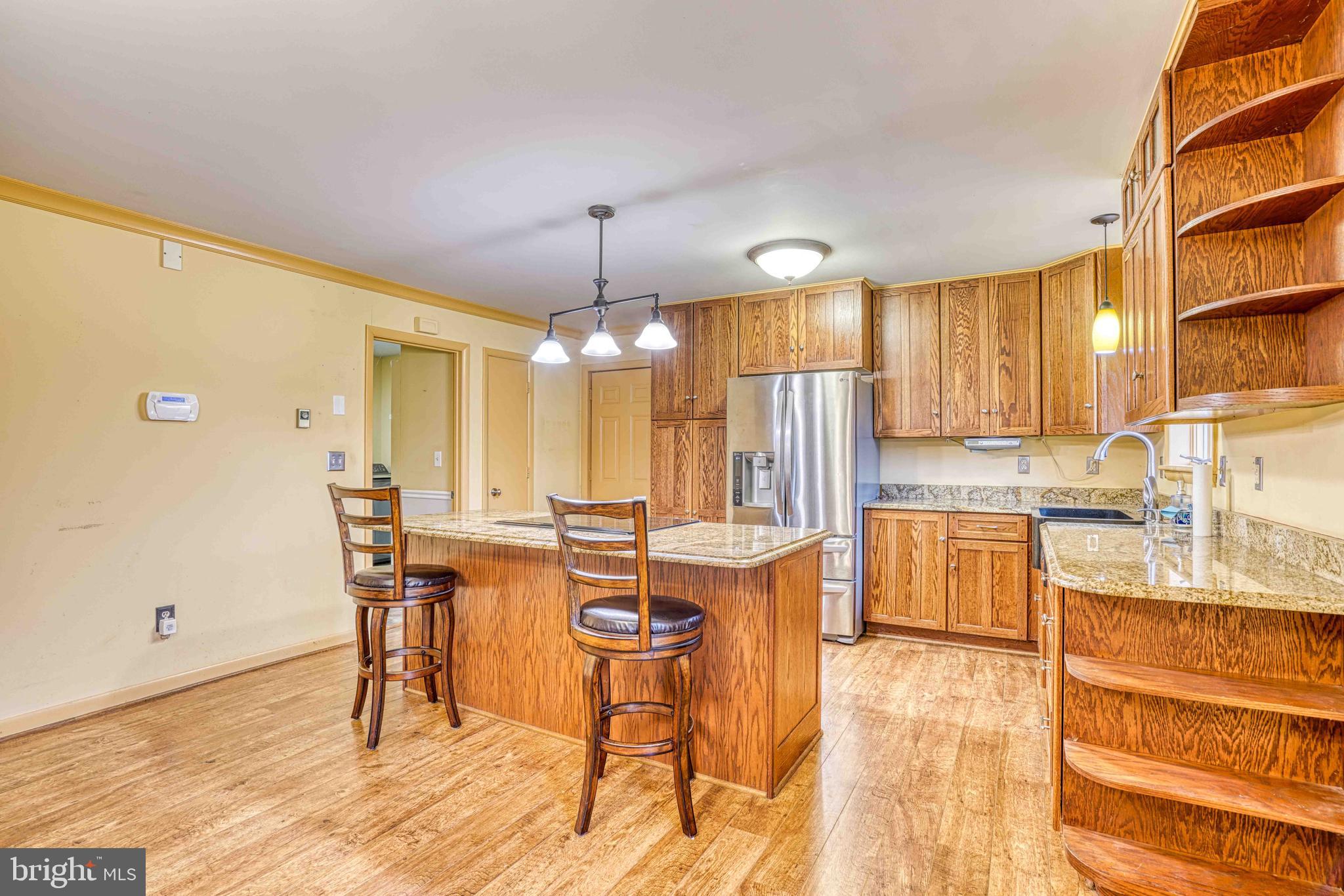 14957 Cherry Lane Ridgely, MD 21660 - Photo 11 of 66 a view of a kitchen with kitchen island granite countertop wooden floor cabinets and stainless steel appliances