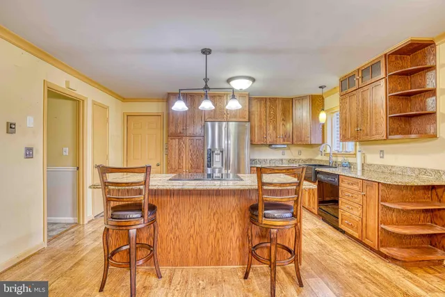a view of a kitchen with kitchen island granite countertop wooden floor cabinets and stainless steel appliances